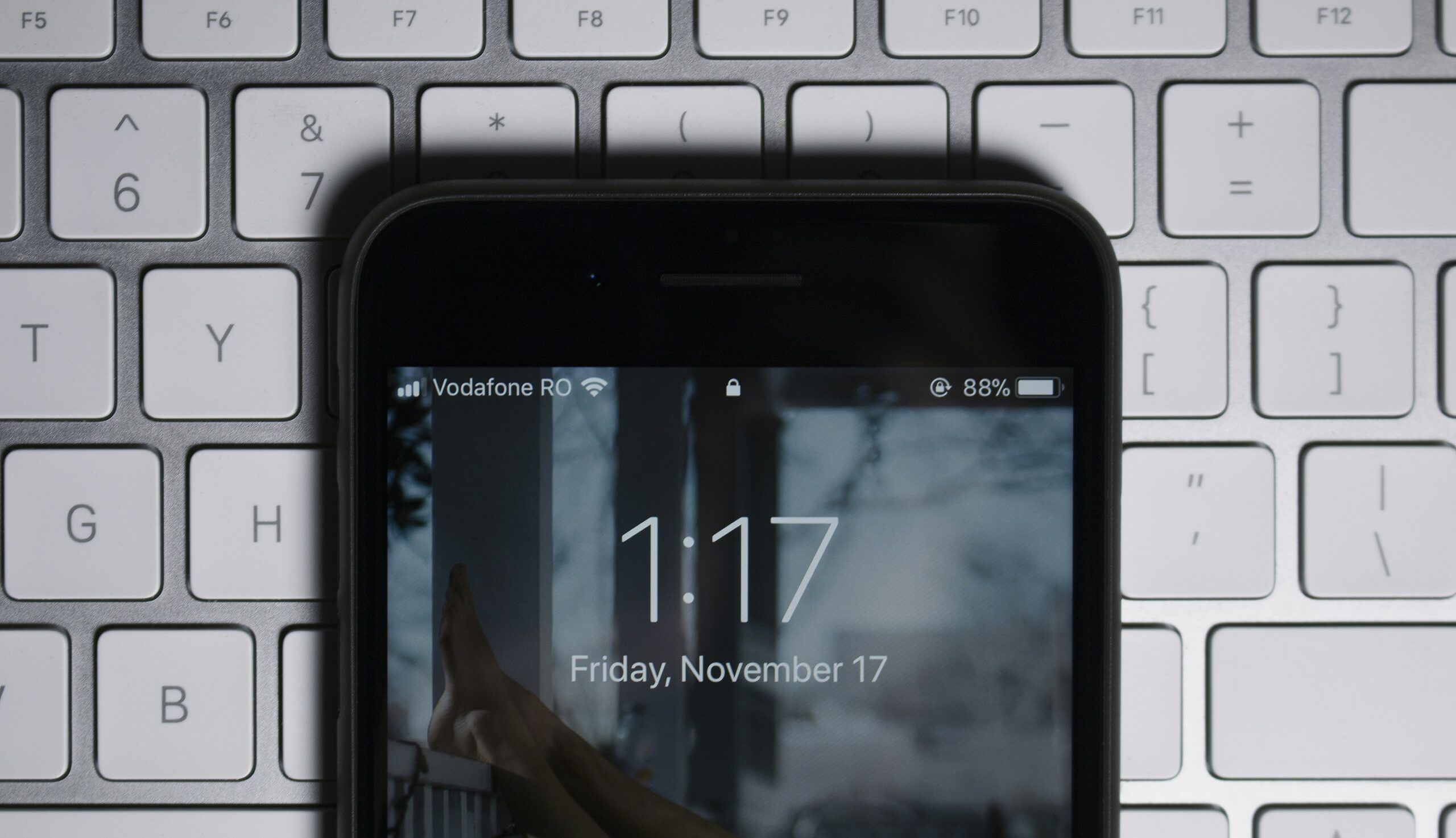 Smartphone displaying the time and date on a keyboard.