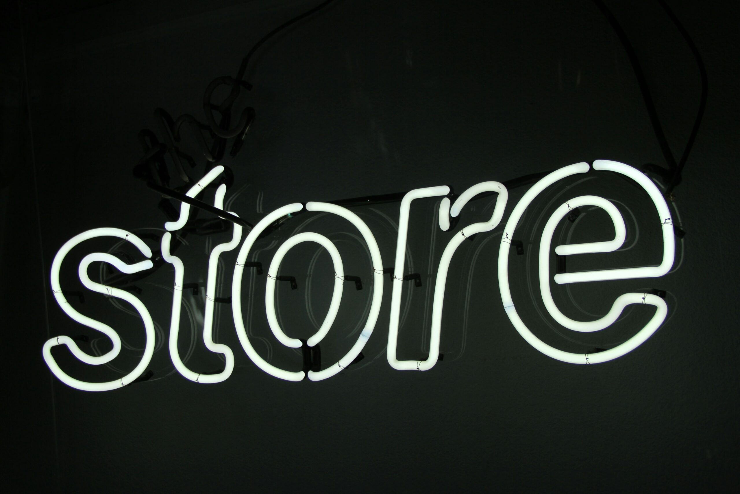 Neon sign that says 'store' in white against a dark background.
