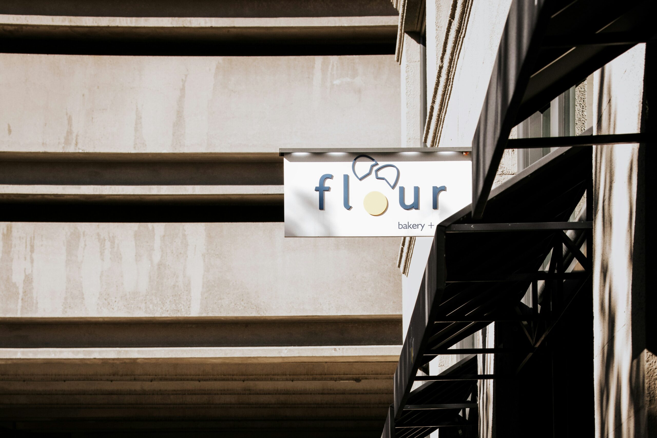 Sign for a bakery named 'flour' with a unique logo on a building facade.