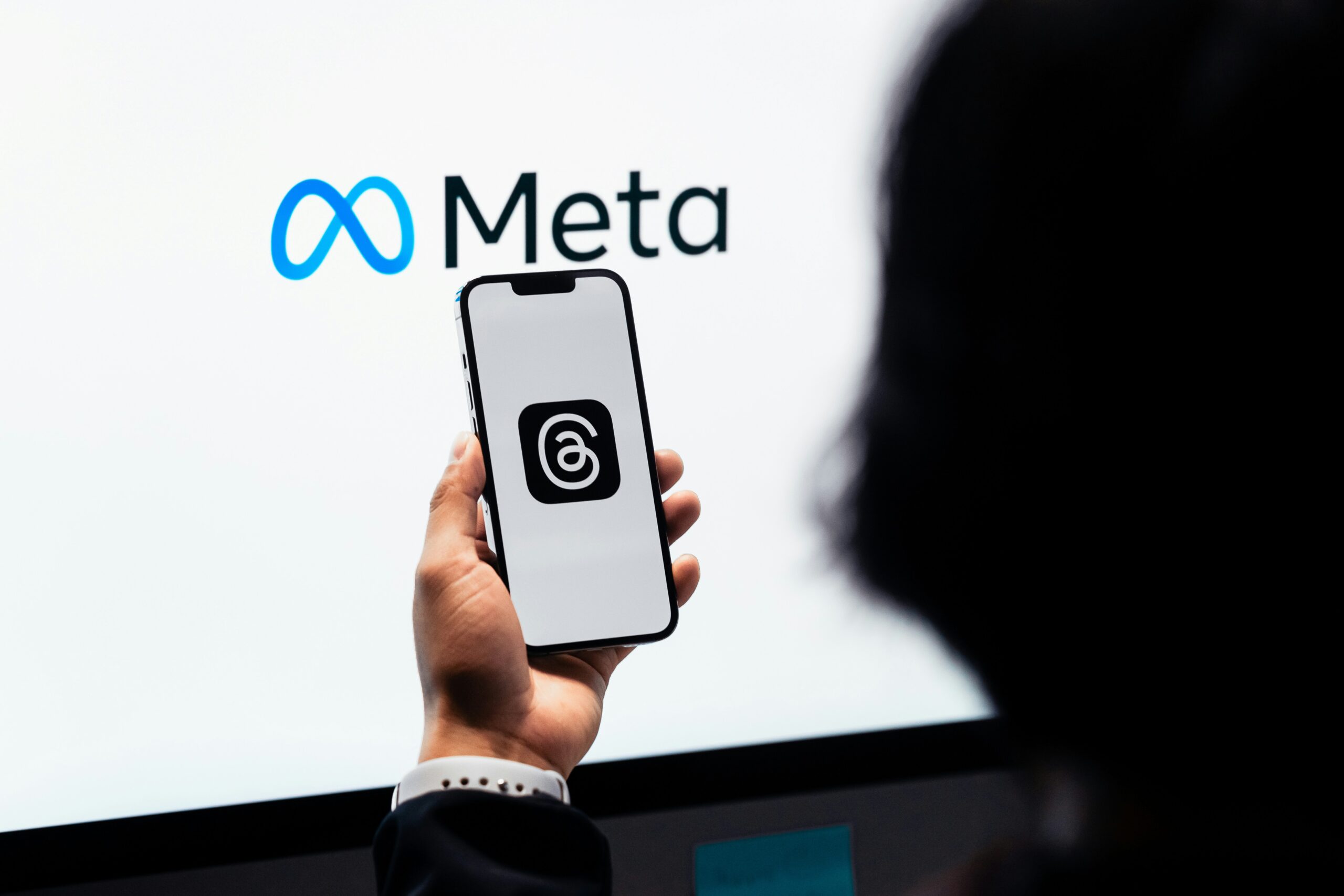 Person holding a phone displaying the Meta logo. Optimize Instagram ad campaigns with Meta.