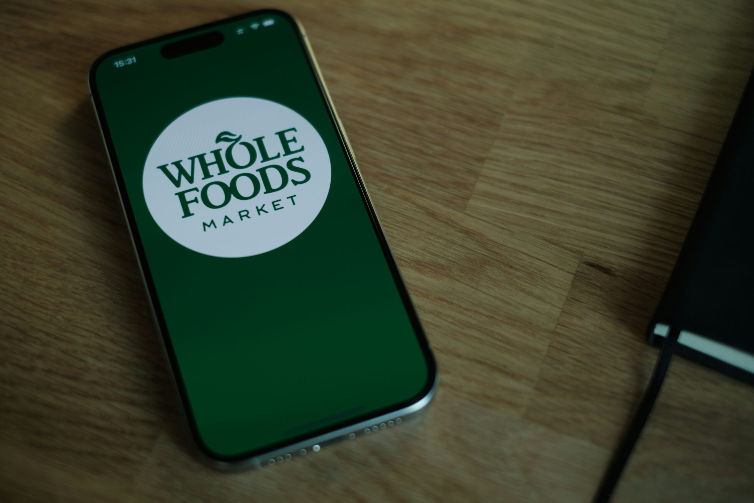 Whole Foods Market app logo on a phone. Improve your app ranking with ASO and drive organic downloads.