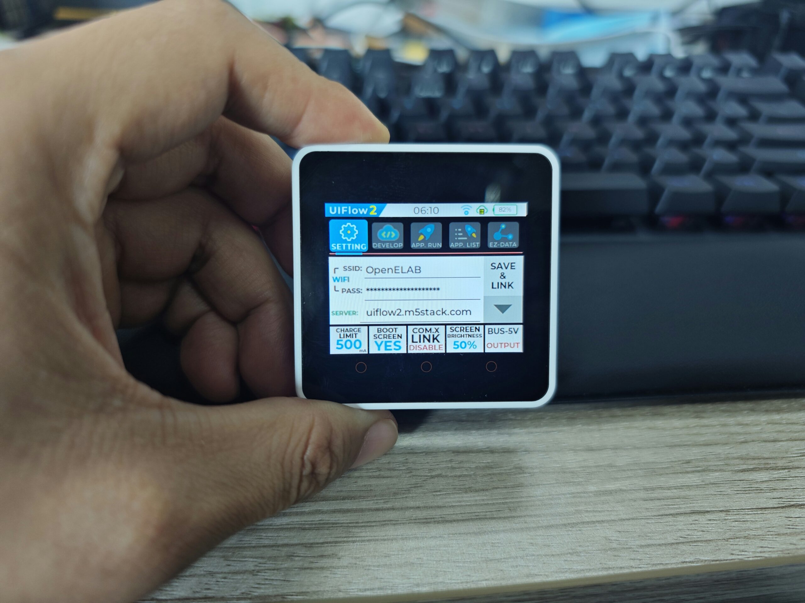 Hand holding a small device with a screen.