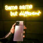 Hand holding a phone, neon sign: