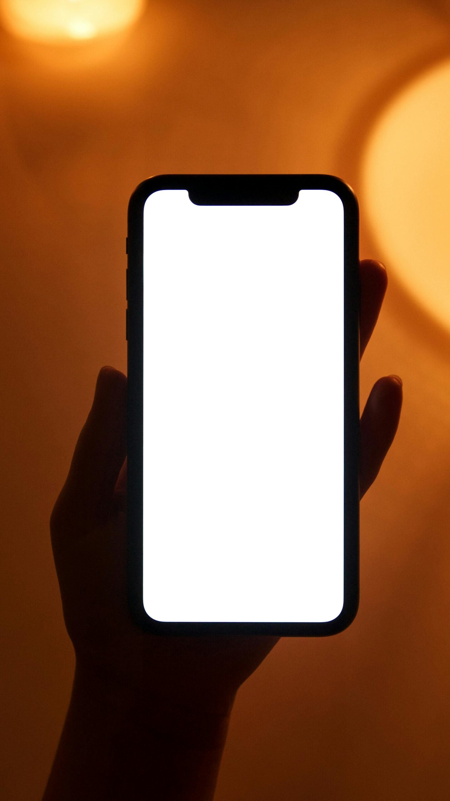 Person holding smartphone with blank white screen.
