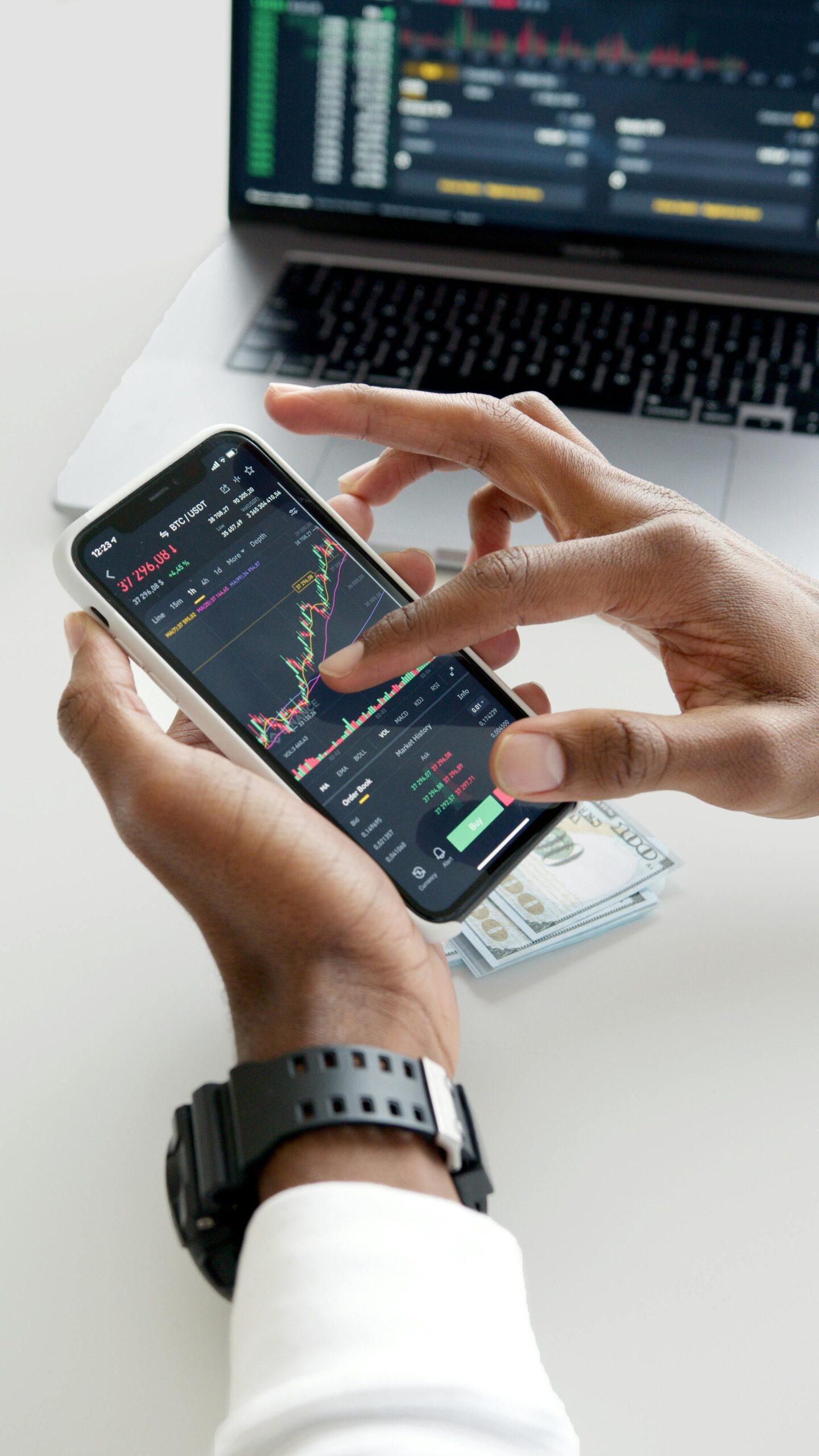 Person using a phone with a stock chart, analyzing market data for strategy.