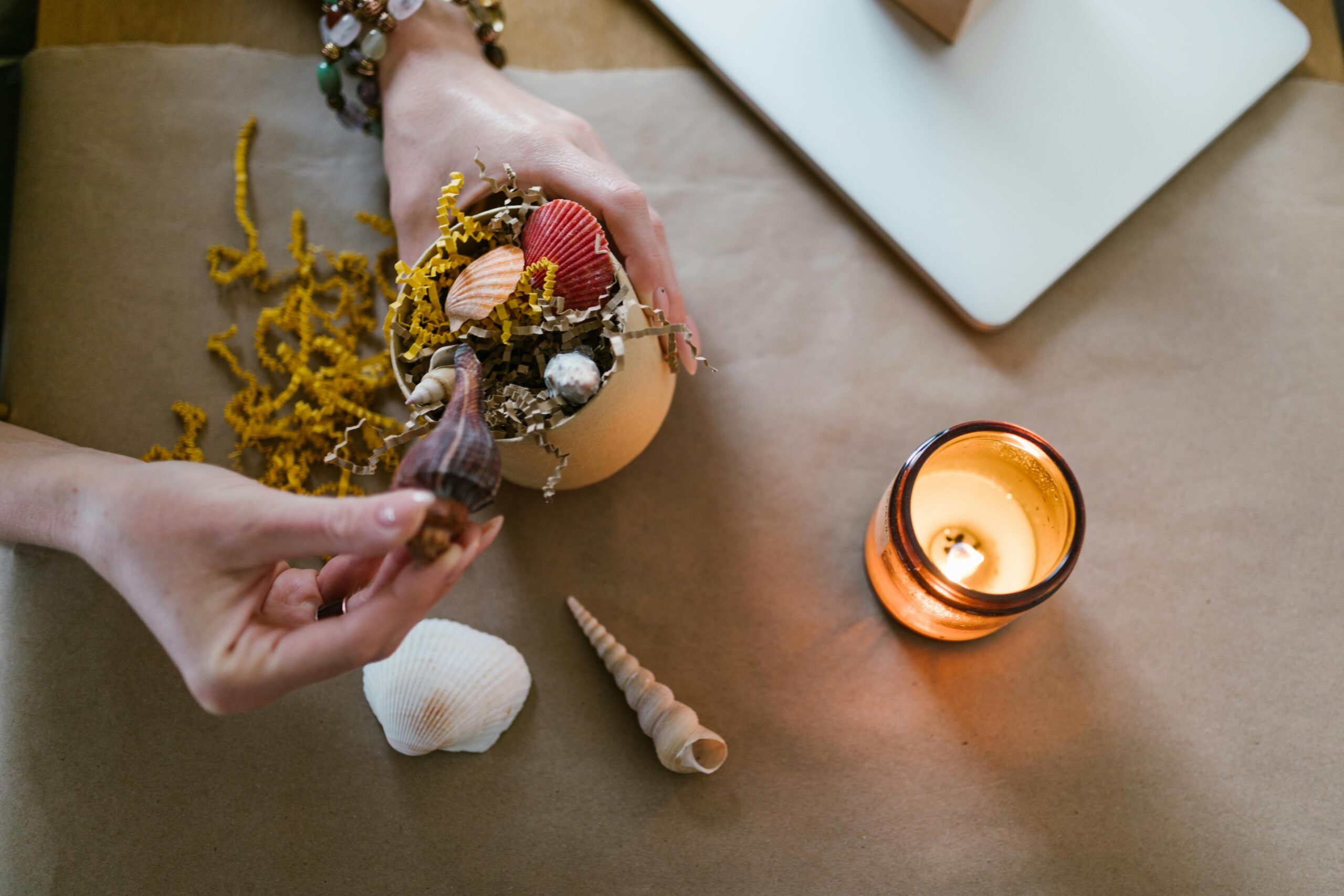 Person arranging seashells on a table.