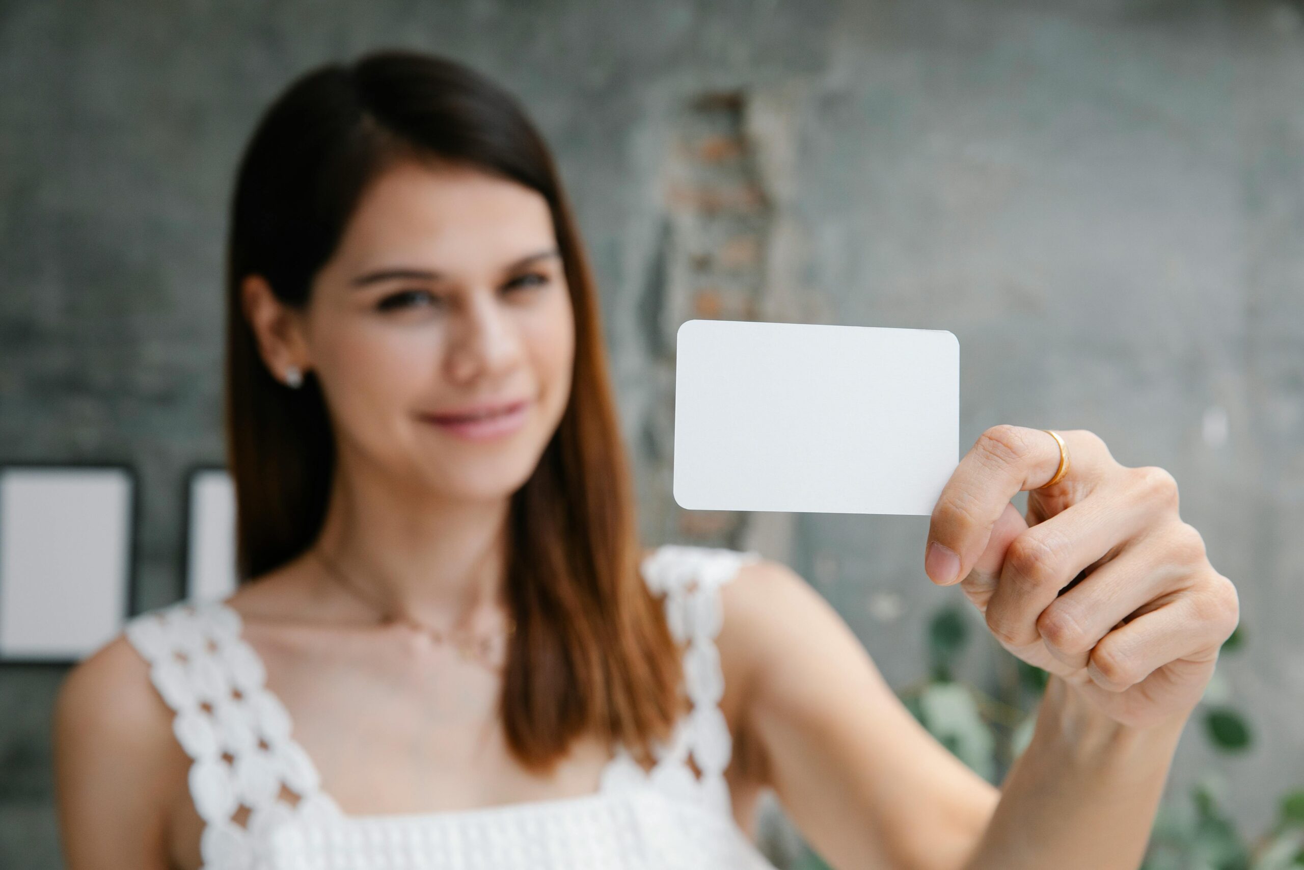 Woman holding a blank business card; marketing, branding concept.