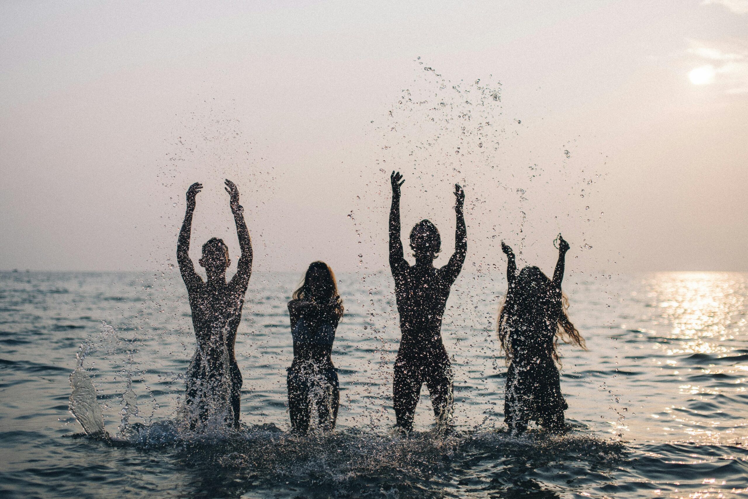 Silhouettes of people in the ocean raising their arms. Great for social media marketing.