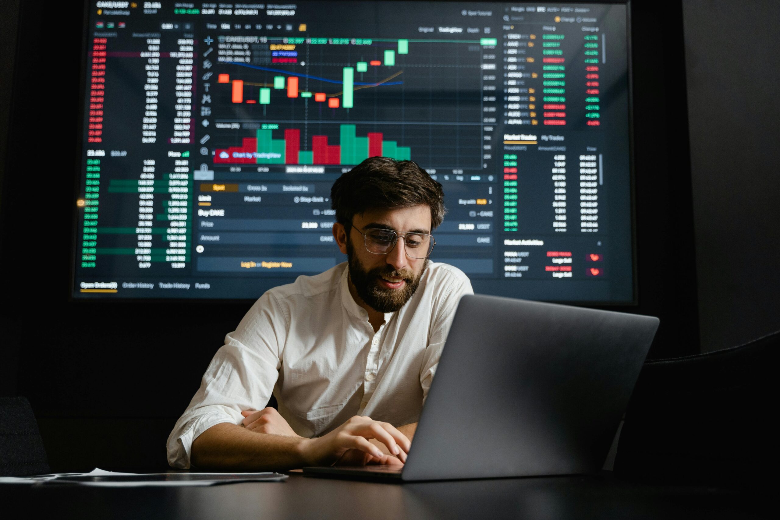 Man using a laptop with stock market charts, showing the use of paid advertising.