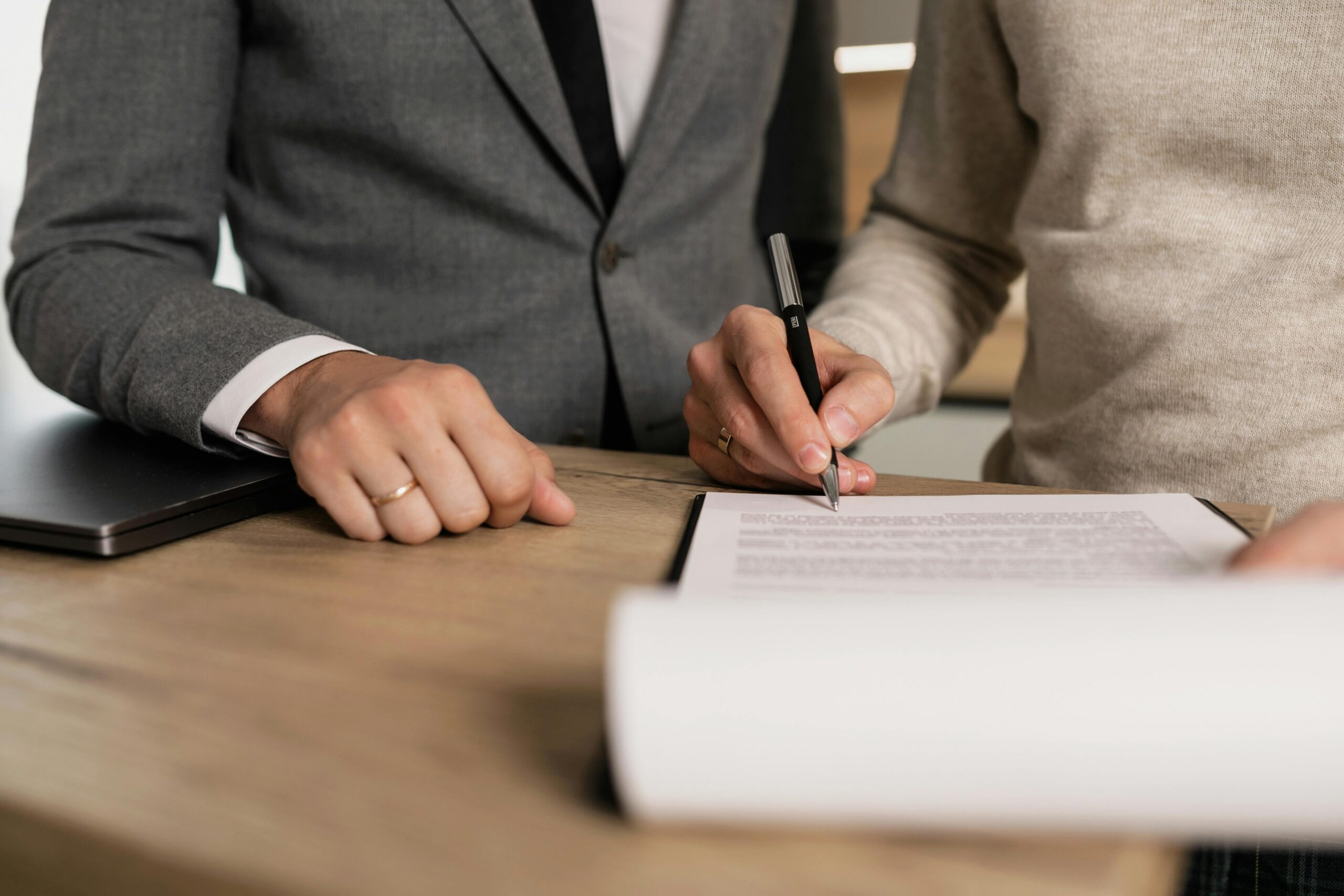 Person signing a document, close-up of hands and pen. 