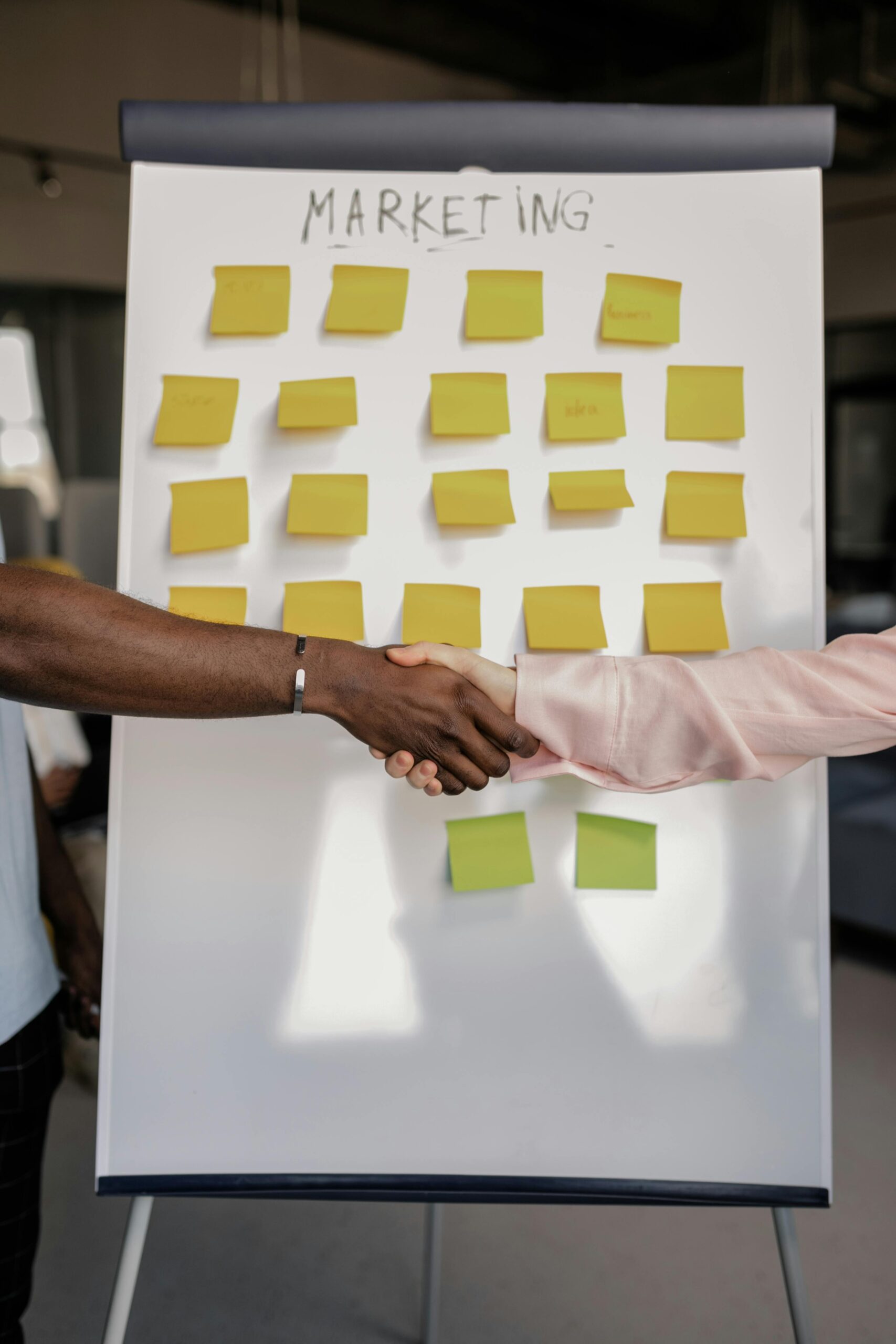 Business handshake in front of a marketing strategy whiteboard.