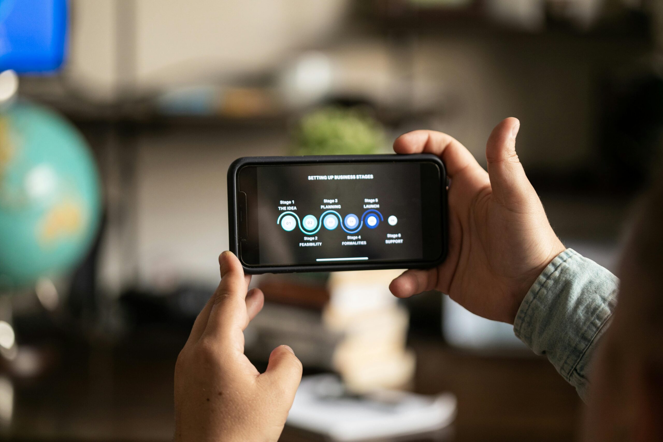 Person holding a phone displaying business stages infographic.