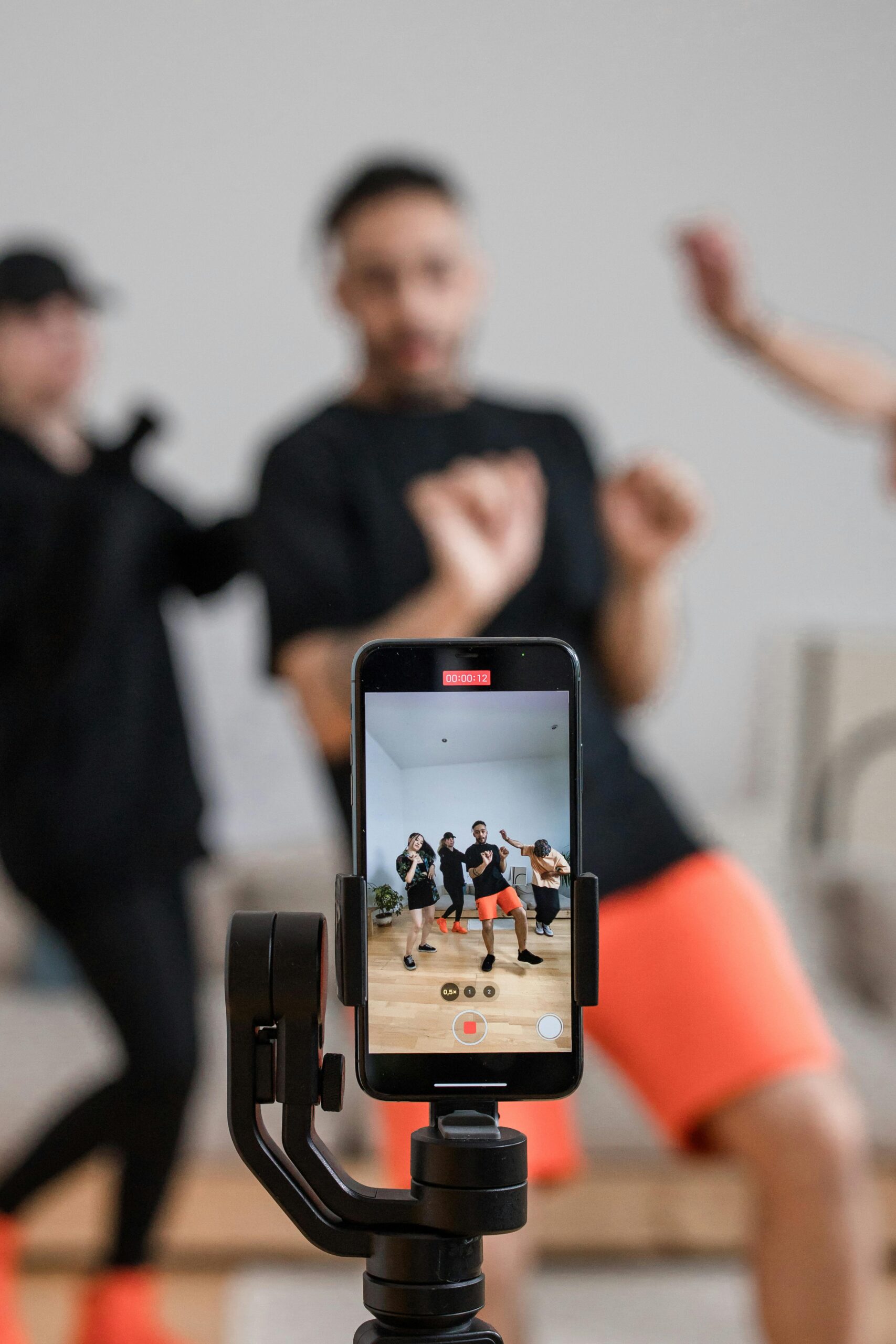 Smartphone recording a dance video; people dancing in the background.
