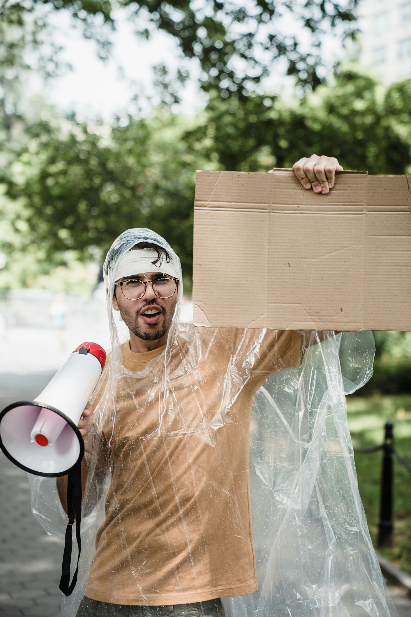 Man in raincoat with megaphone and sign protesting.