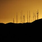 A dynamic cityscape of a major US city at dusk, overlaid with glowing digital network connections, charts, and data streams, symbolizing the convergence of physical and digital marketing. The image should evoke innovation, growth, and connectivity.