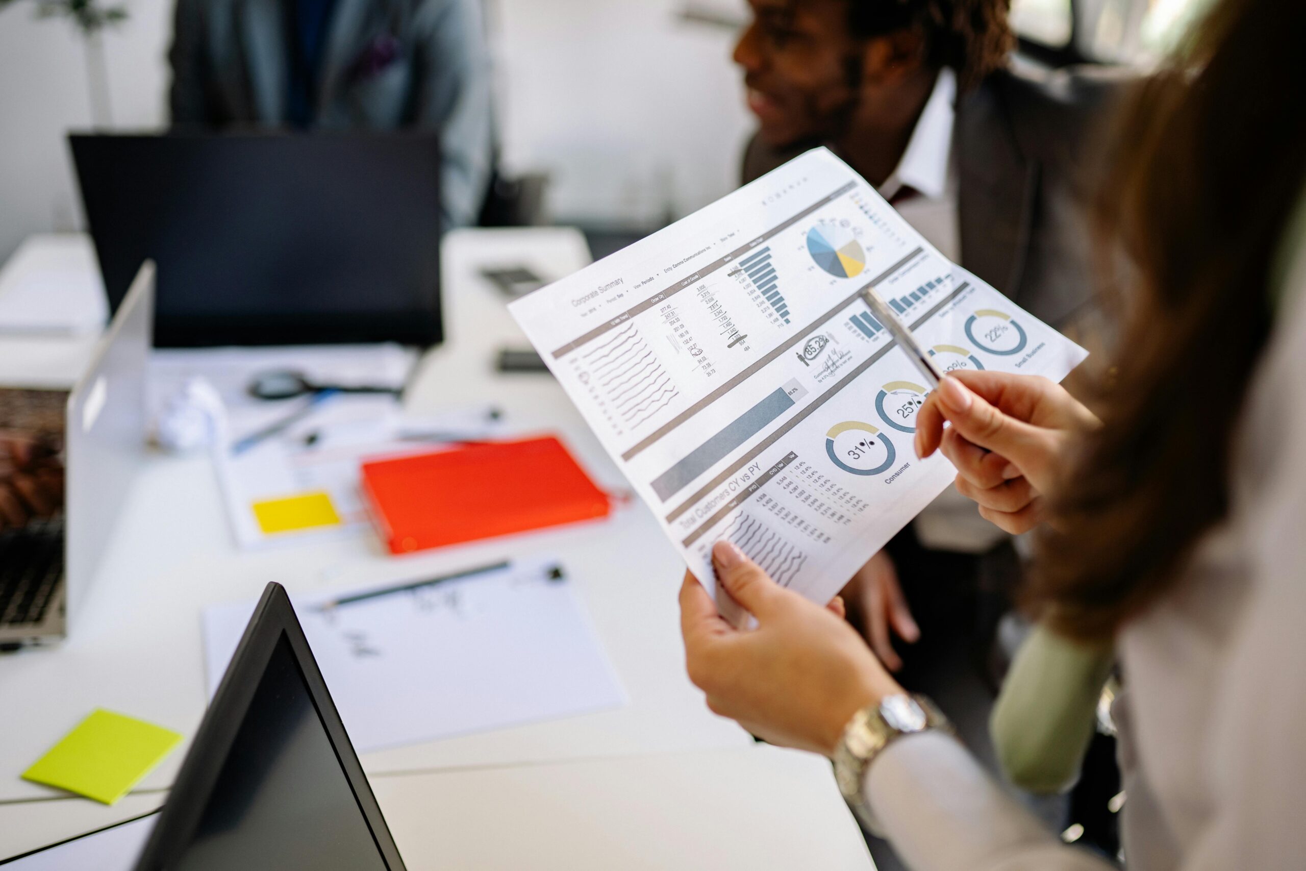 A team of diverse marketing professionals collaborating around a large screen displaying Meta ads performance data. The atmosphere is energetic and positive, with team members pointing and discussing strategies.