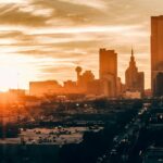 A vibrant cityscape of a major Texas city (e.g., Austin, Dallas, Houston) at sunset, overlaid with data visualization elements representing ROI growth from Google Ads campaigns. The color scheme should be professional and trustworthy, with blues and greens dominating.
