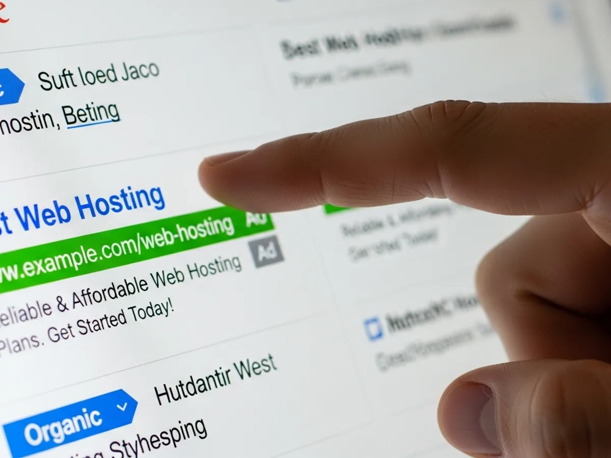 Close-up of a finger about to click on a web hosting ad in search results, illustrating the use of PPC advertising as part of online growth strategies by a digital marketing agency.