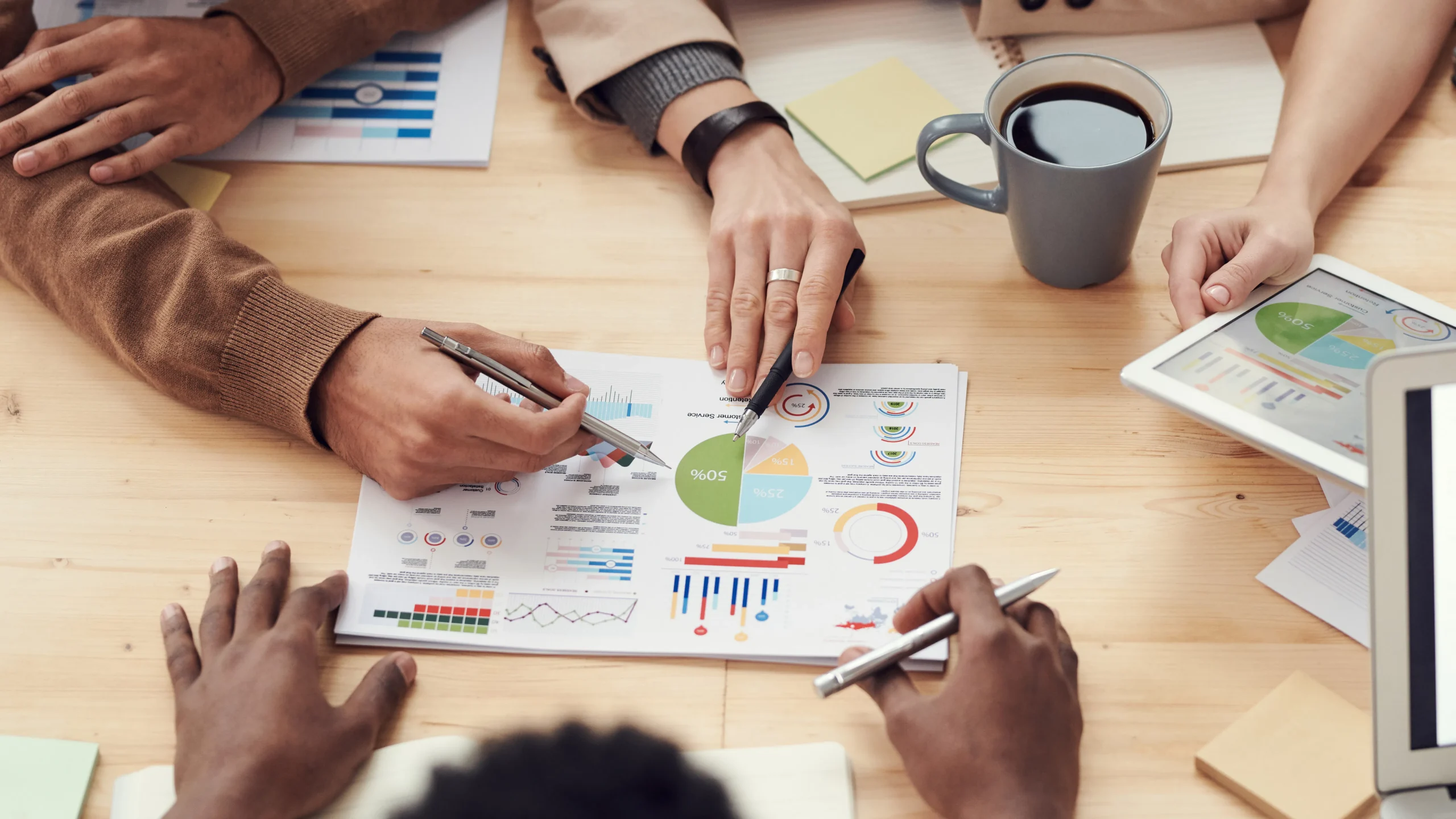 A team of marketing professionals collaborating on a Meta ads campaign, analyzing data on multiple screens, and discussing optimization strategies.