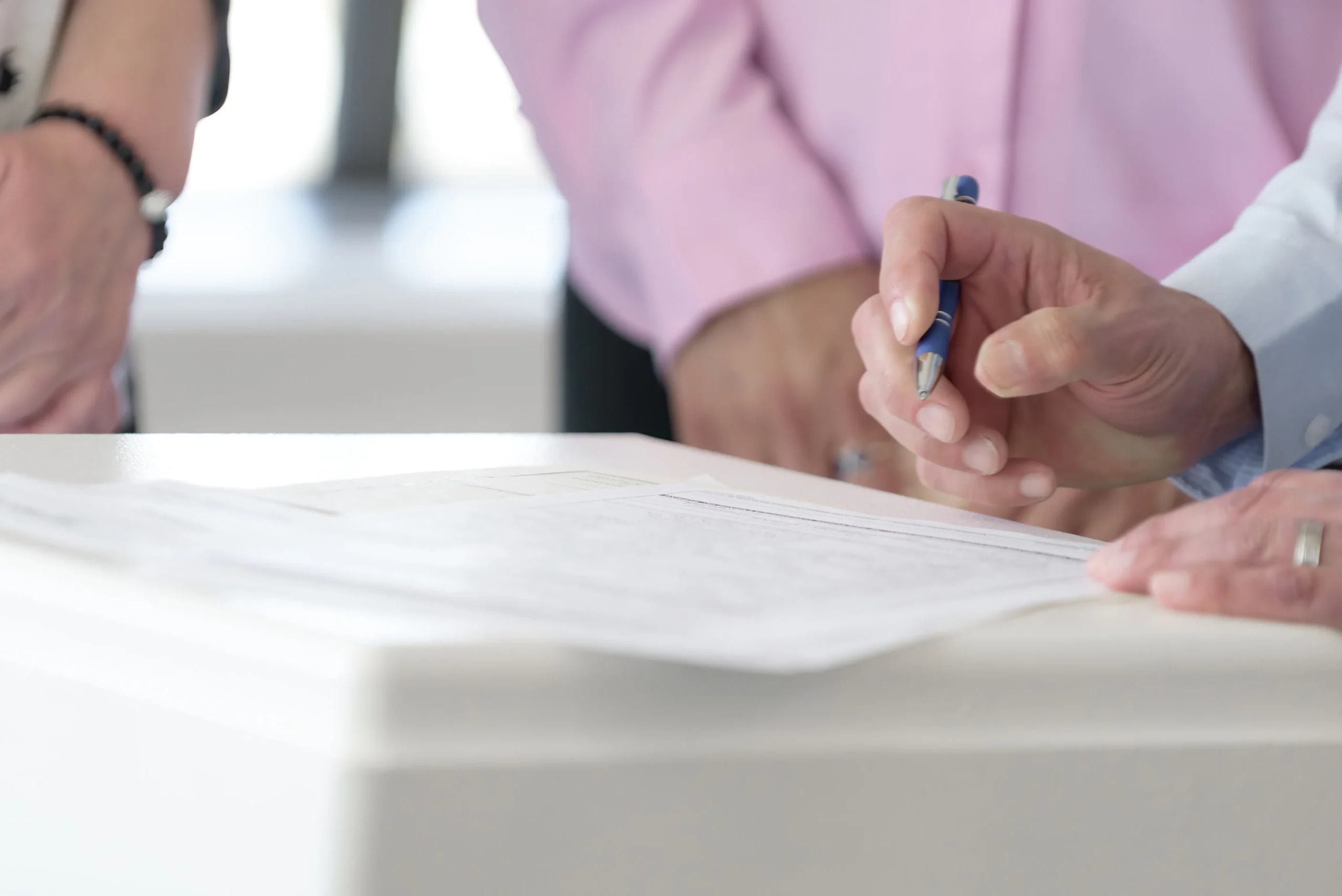 Man signing document with pen on white table, possibly related to native ad agency agreement