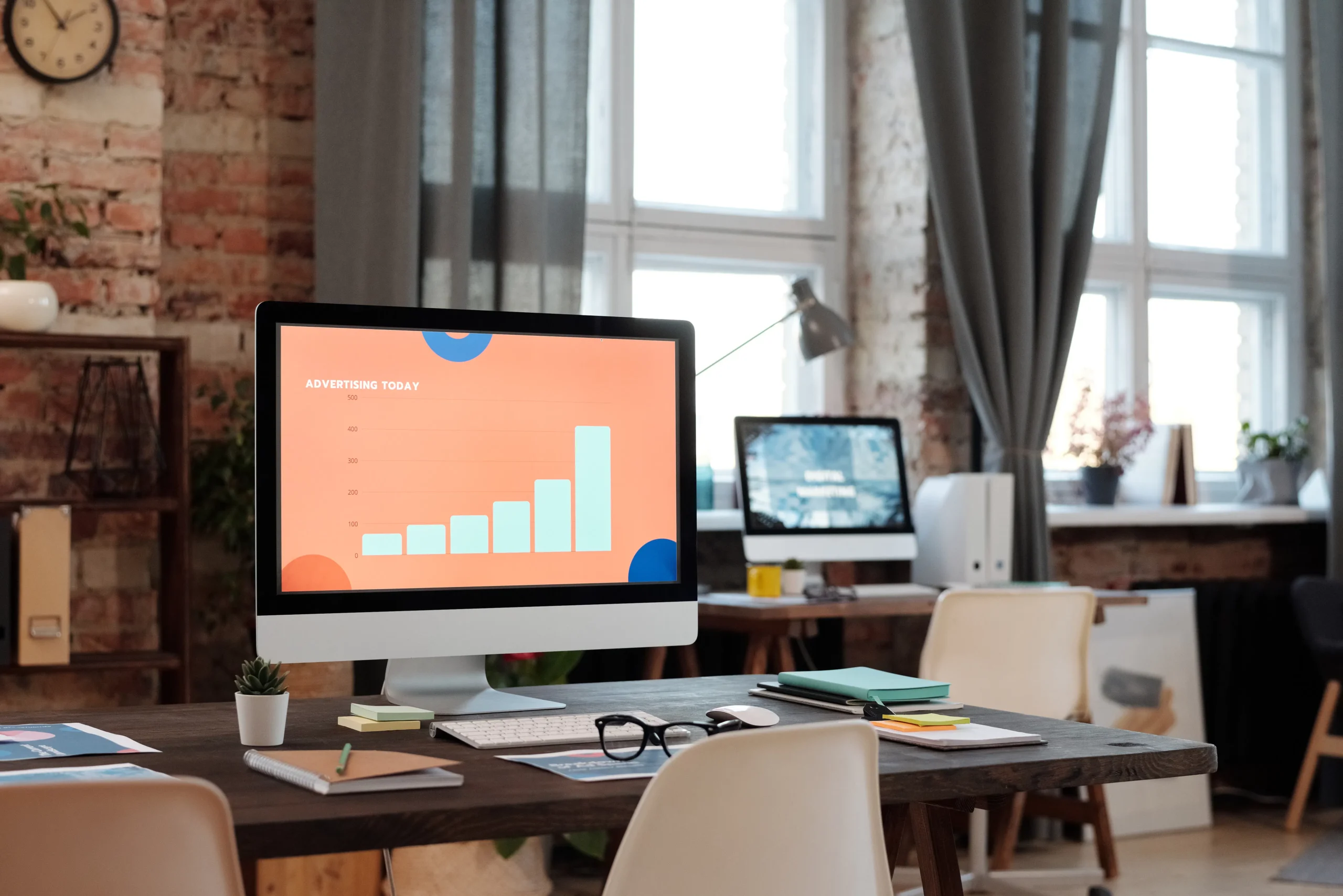 A modern office workspace featuring a computer monitor displaying an advertising today graph, showcasing data for native digital advertising campaigns.