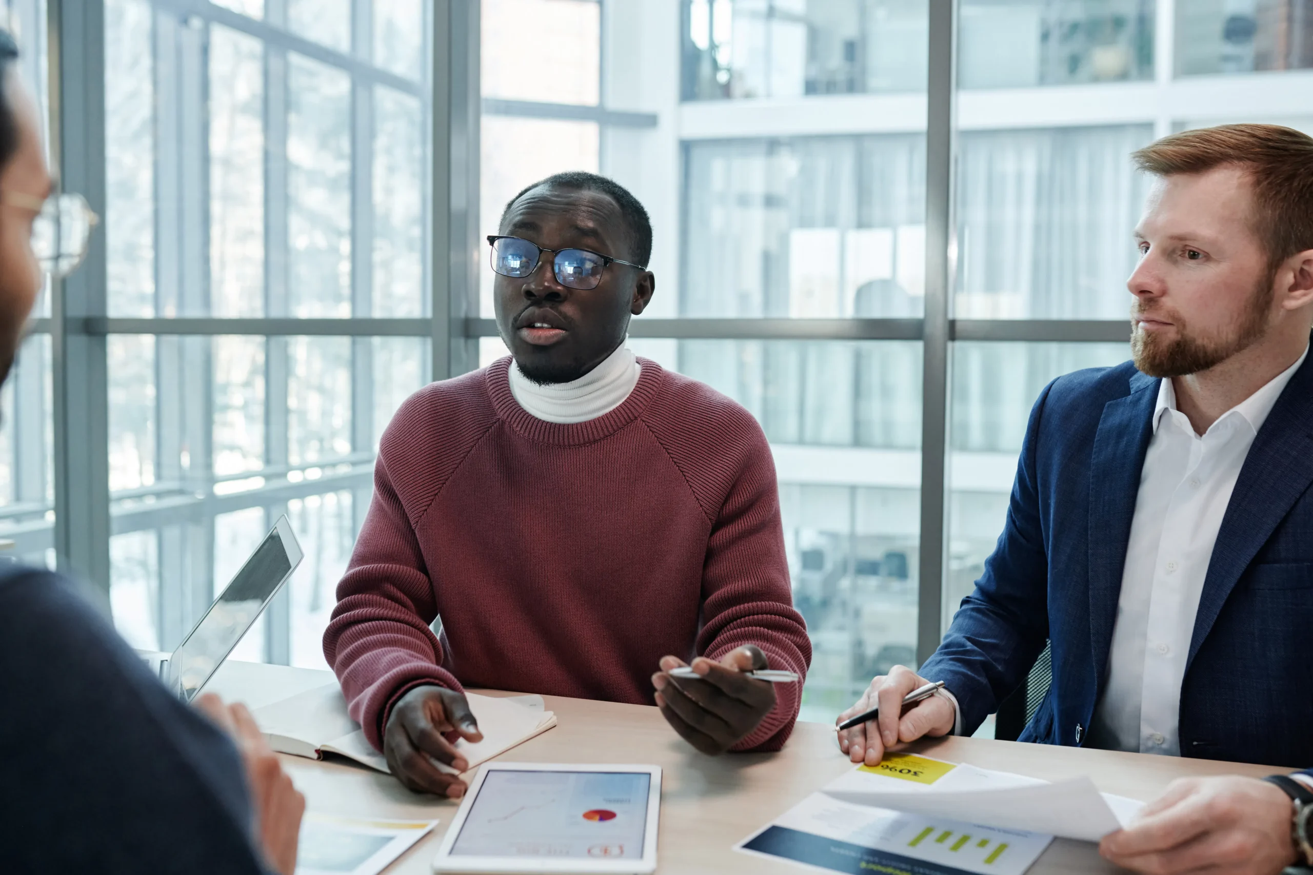 Business professionals discussing native content marketing strategies in a modern office setting, reviewing data on a tablet during a meeting.