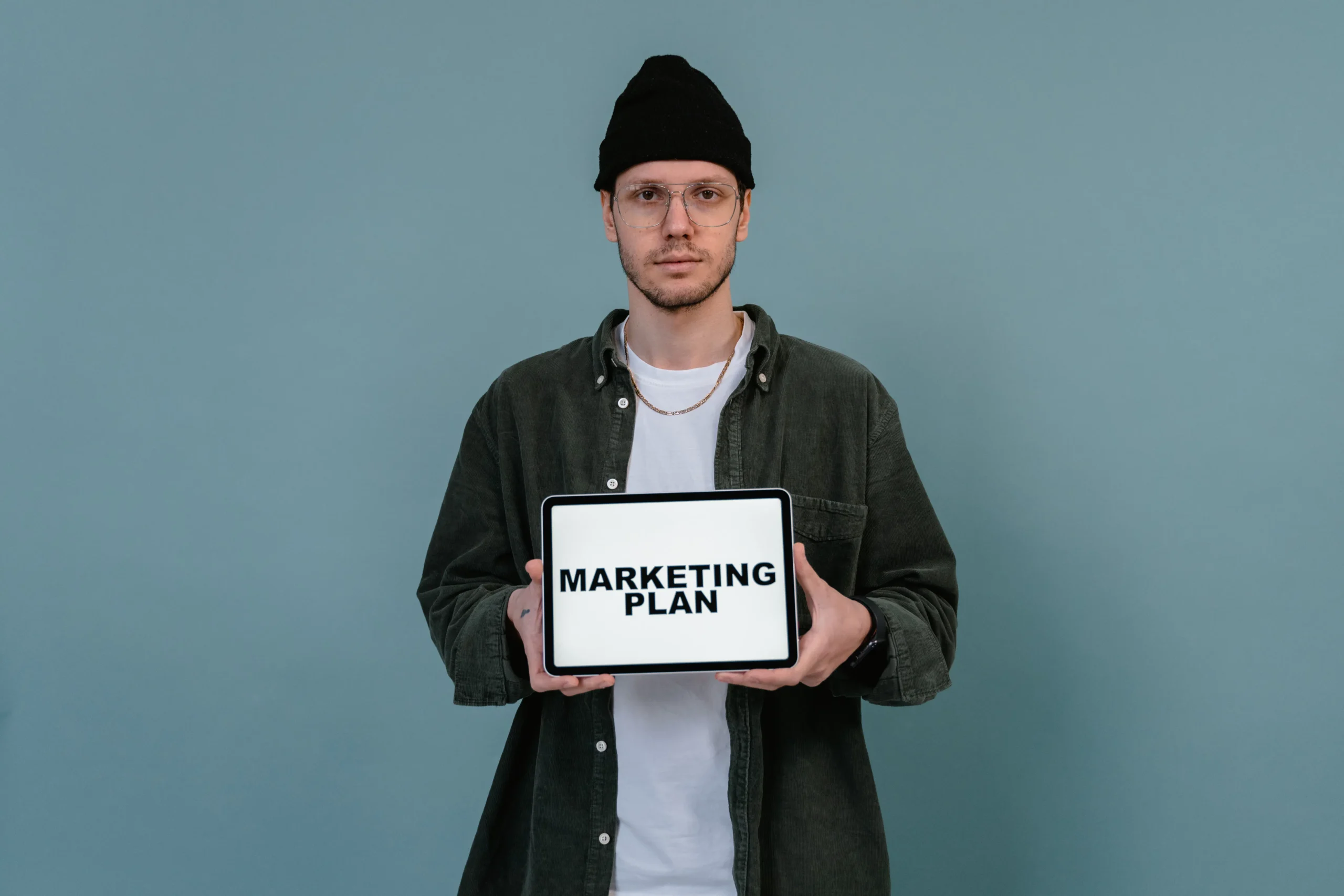 Man holds tablet displaying 'Marketing Plan' for a digital marketing business strategy.